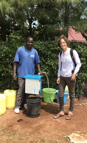 A man and a woman are standing next to a water dispensing device in an outdoor setting.