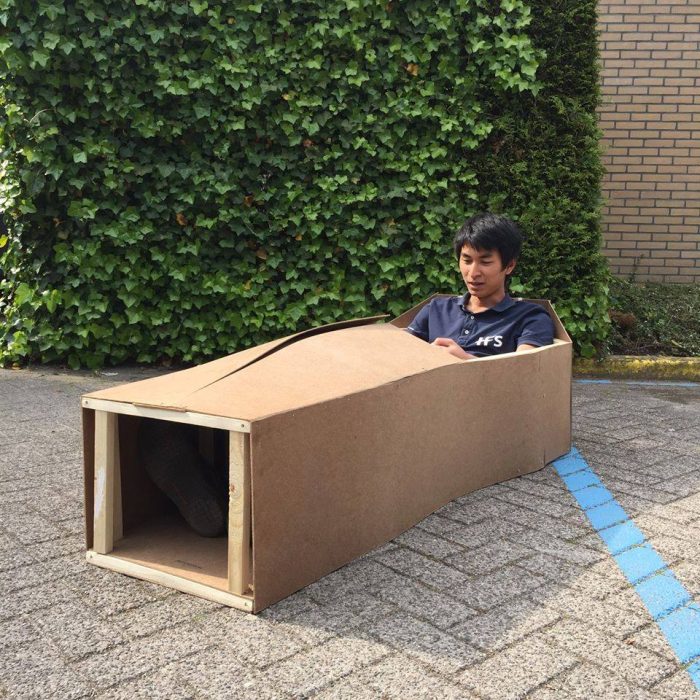 Pun Praphanphoj sits inside a simple, homemade wooden vehicle prototype, shaped like a race car without wheels.