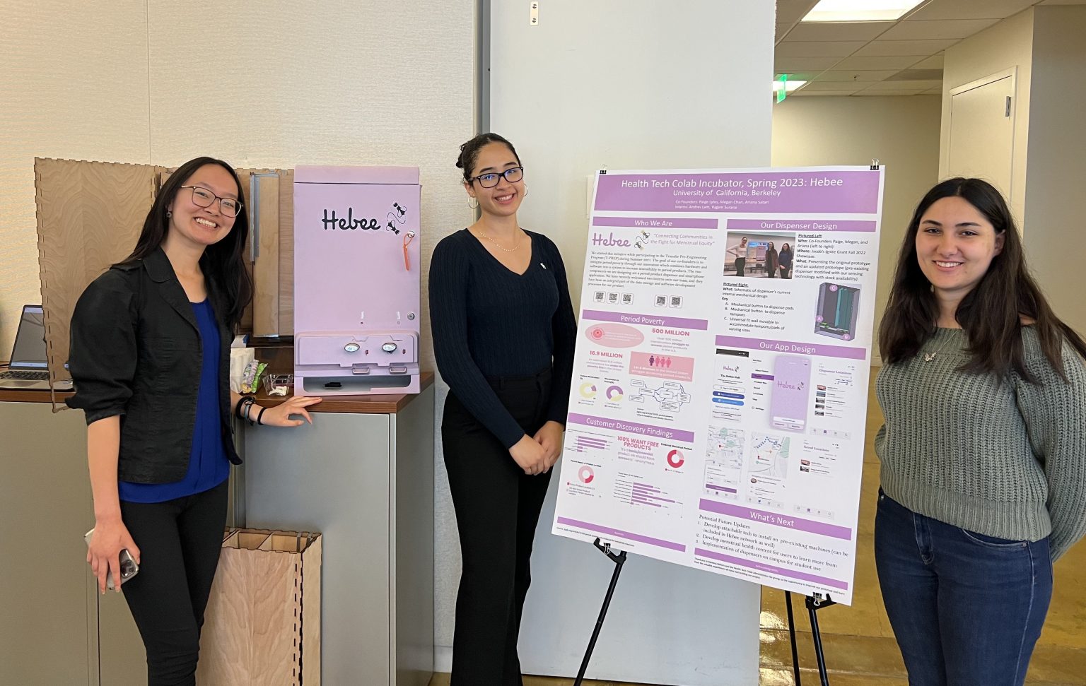 Ariel Ho, Midori Pierce, and Tiffany Luo next to the poster and prototype of their project Hebee.