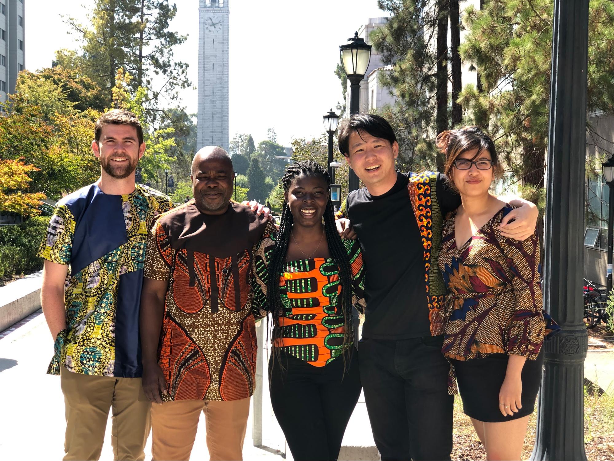 Five members of the MDevEng community sport SHE 4 Change colorful clothing with bold patterns.